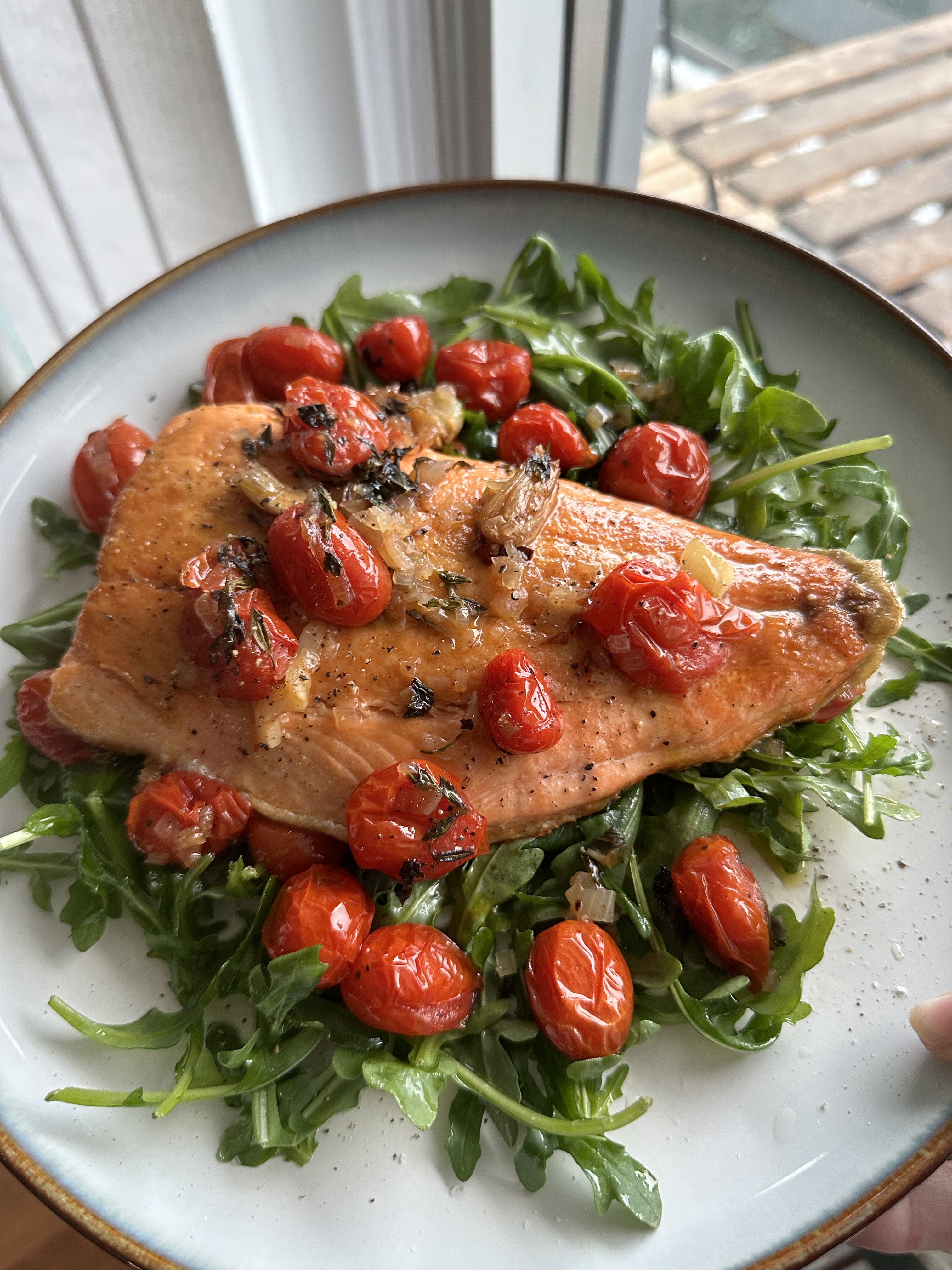 salmon with confit tomatoes over a bed of arugula